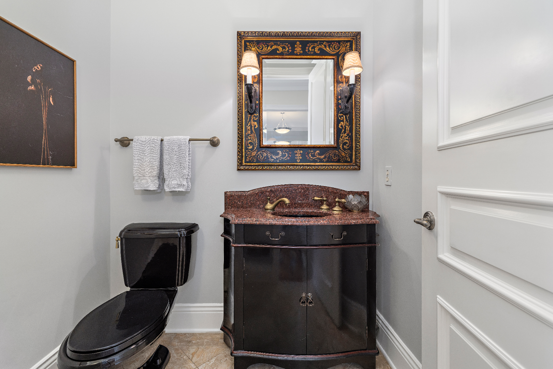 Current main floor powder room with black vanity, red-brown granite counter, and ornate gilt mirror