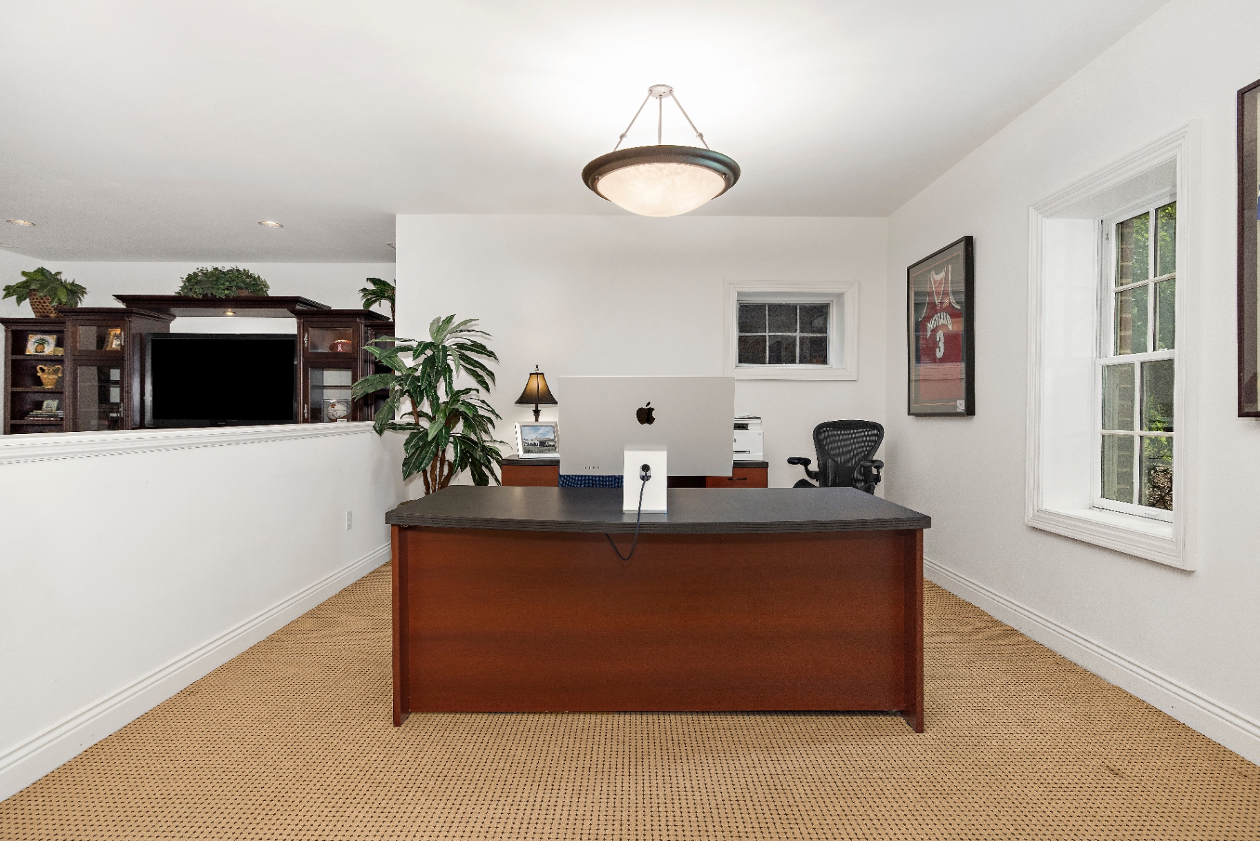 Current lower level office with cherry desk, patterned carpet, and built-in cabinetry