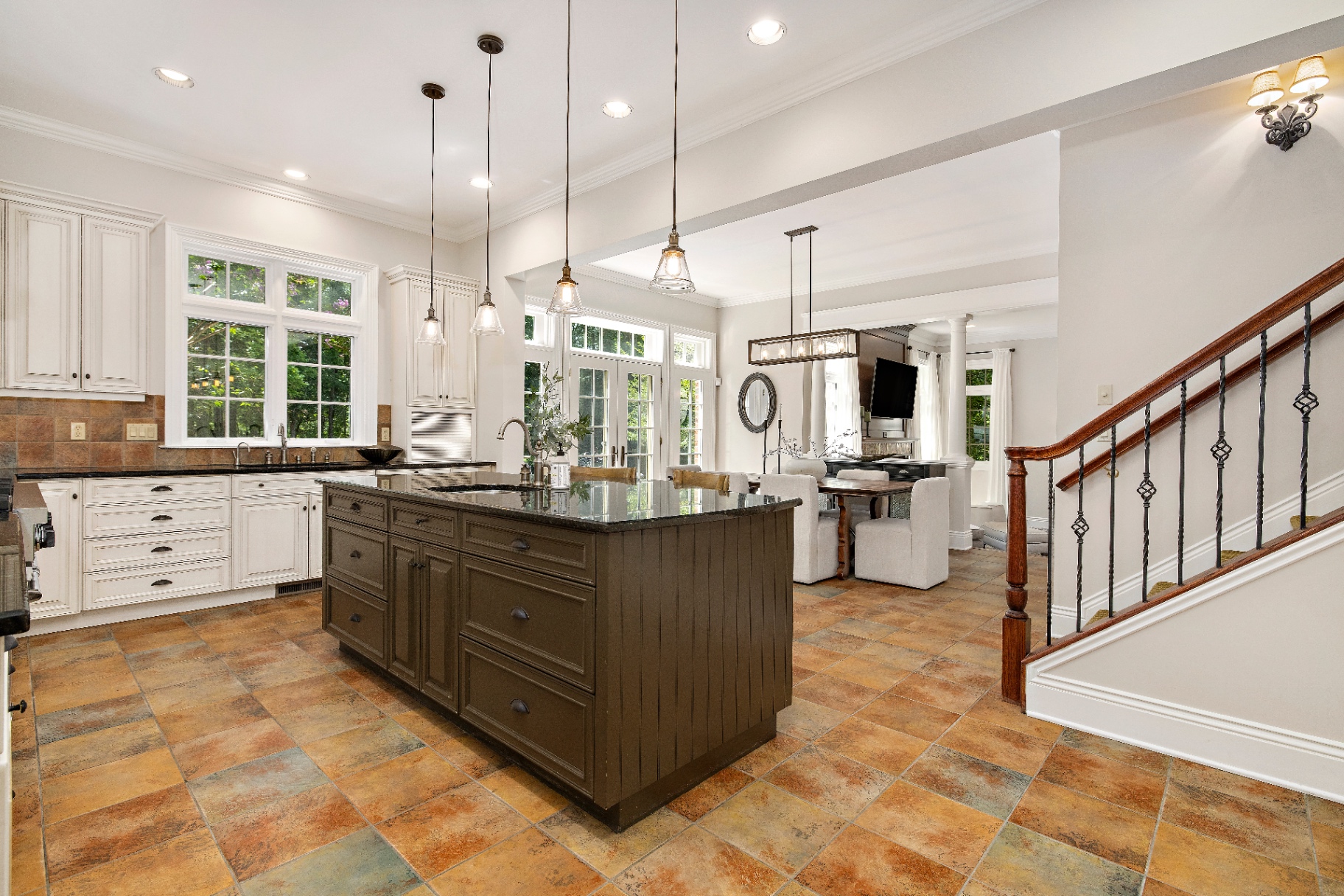 Current kitchen with dark island, terra-cotta tile floor, and white perimeter cabinets
