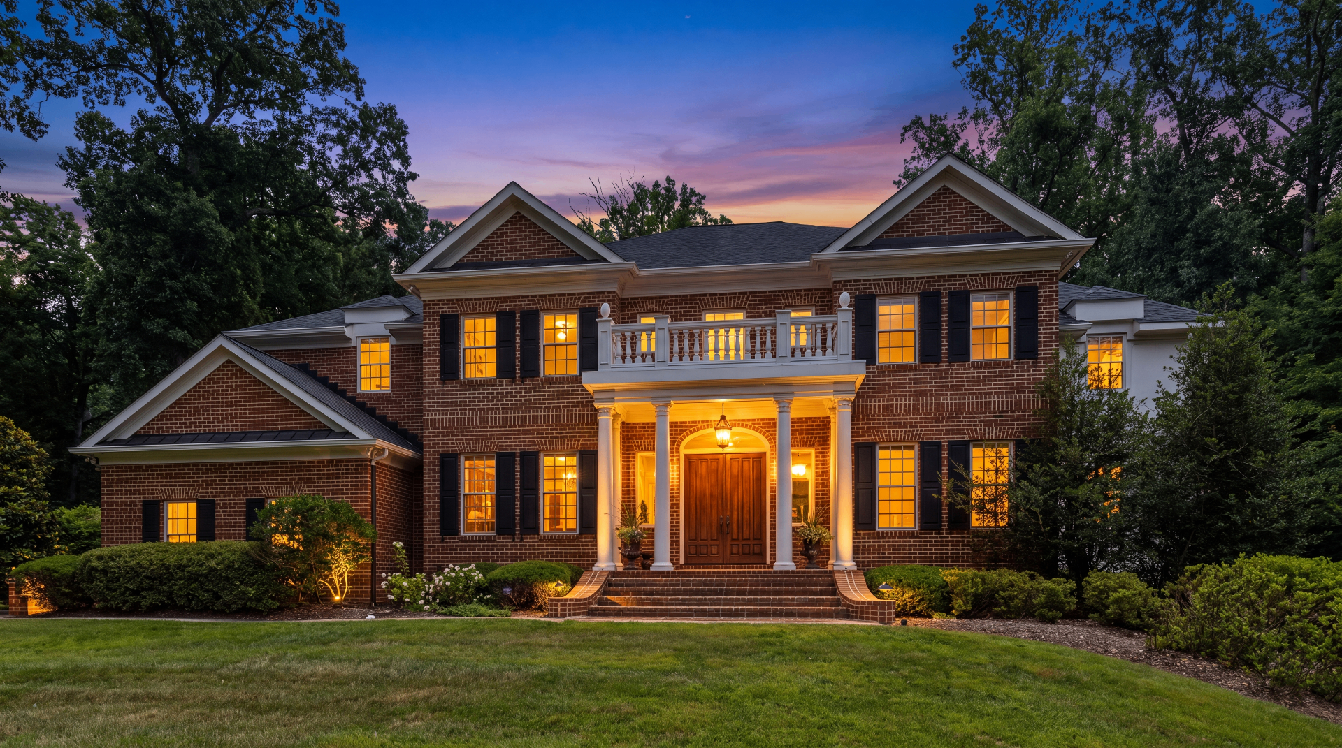 Classic Georgian brick home with white columns and green lawn