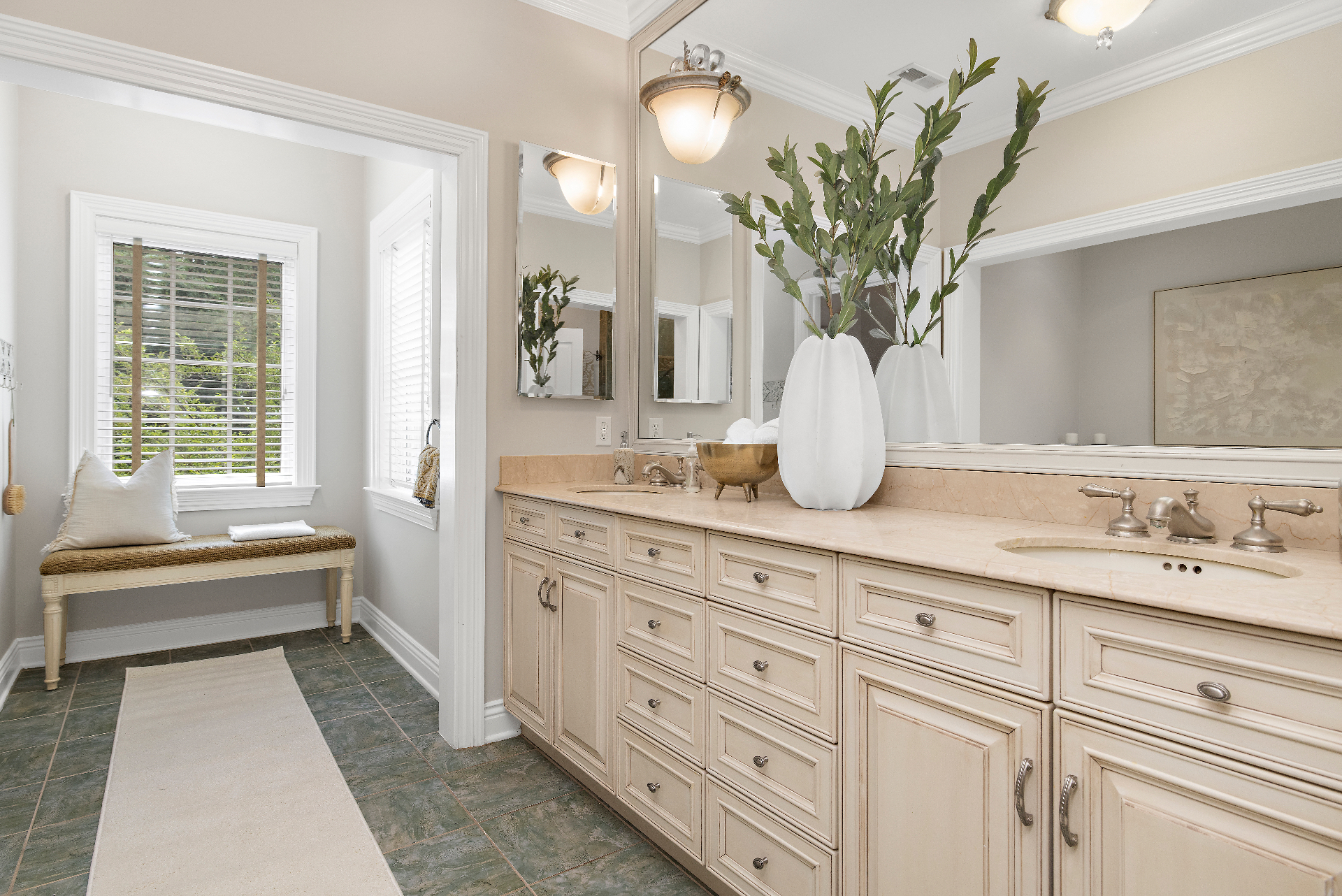 Current primary bath with cream glazed cabinetry, marble countertops, double vanity, and green slate tile floor