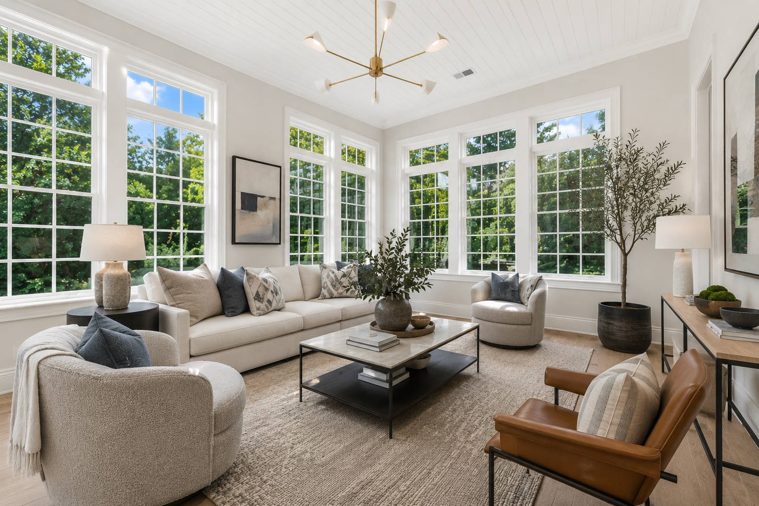 Reimagined sunroom with modern beadboard ceiling, brass sputnik chandelier, cream sectional, and leather accent chair