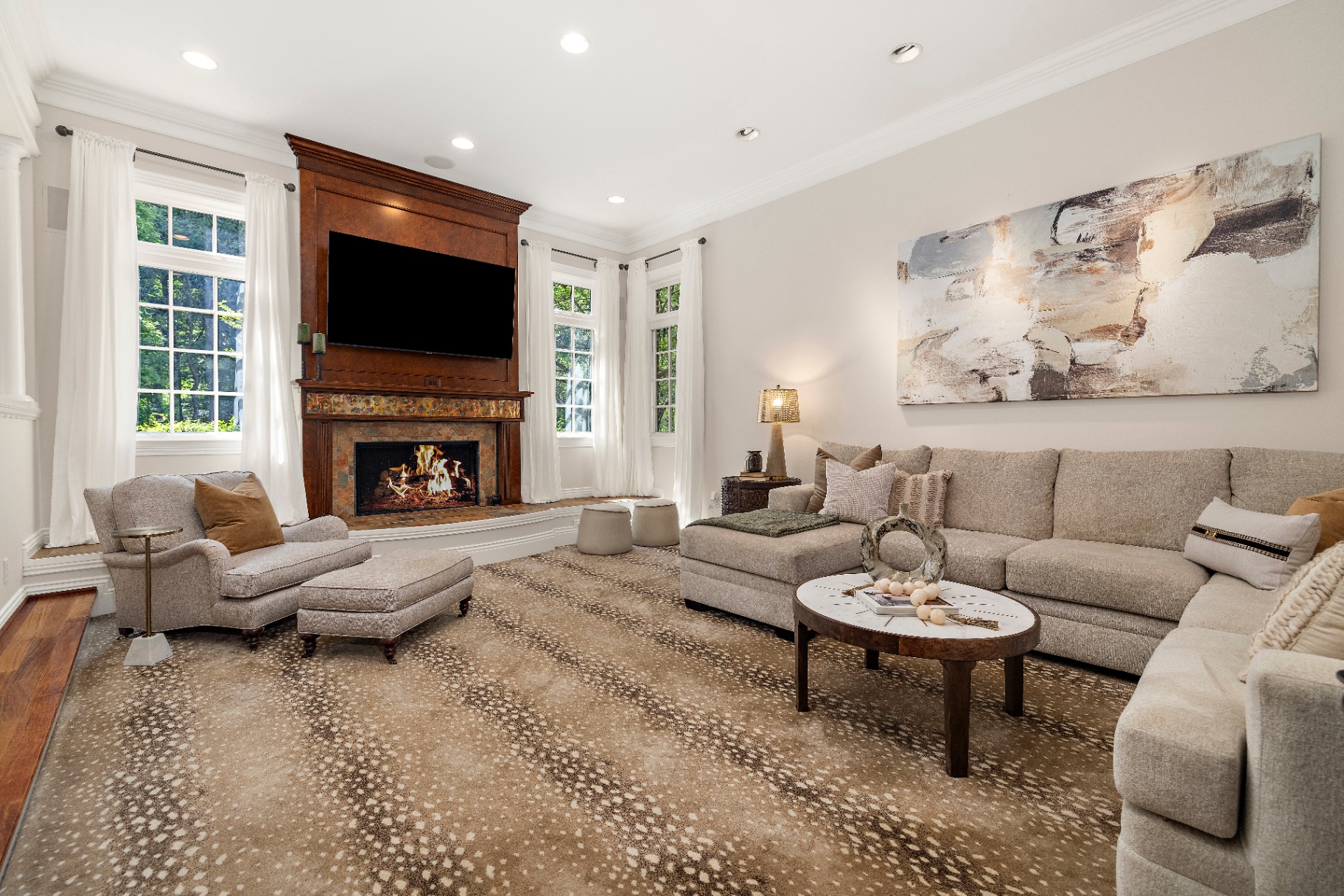 Current family room with neutral sectional, antelope rug, and wood fireplace surround